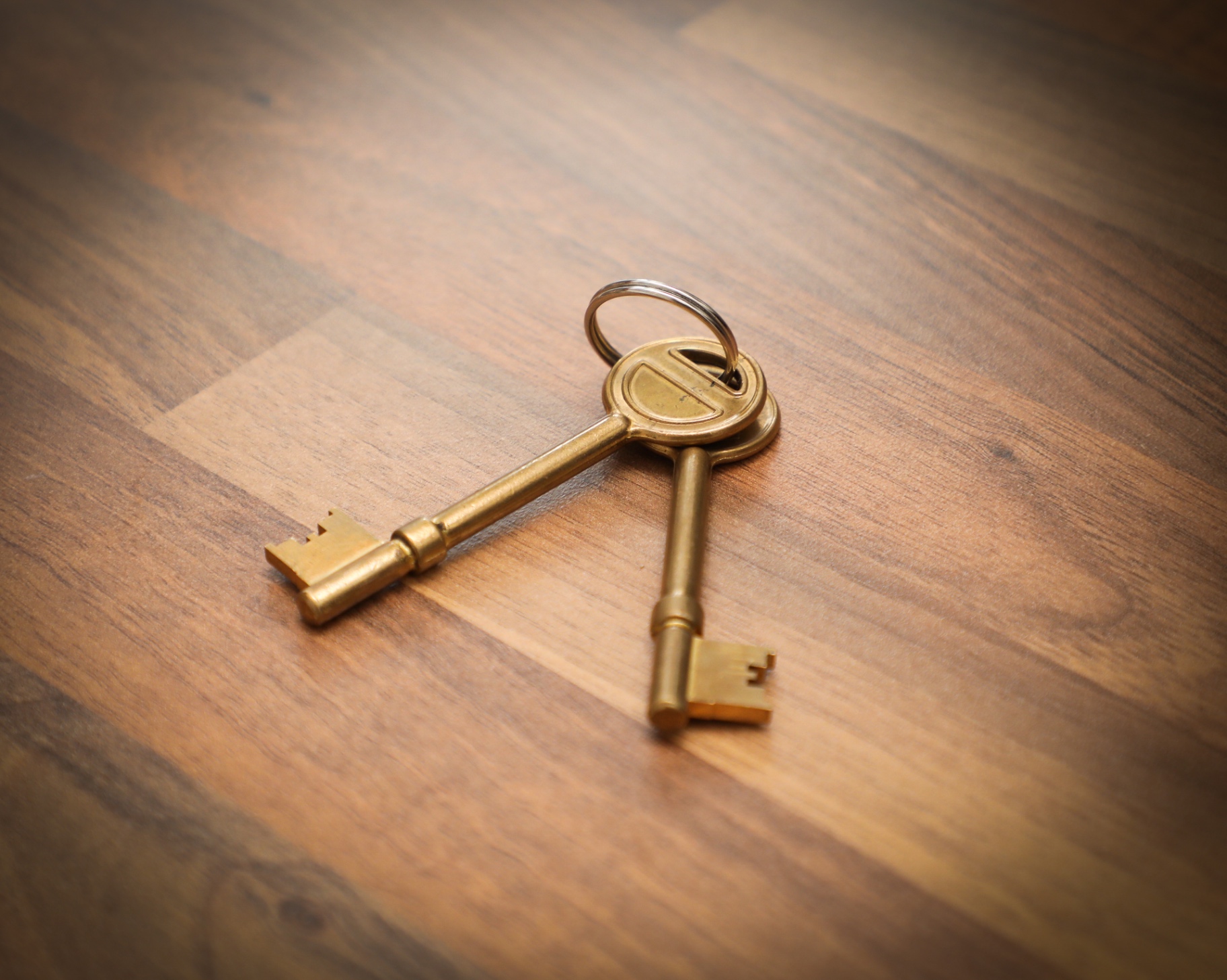 Two brass keys resting on the wooden floor
